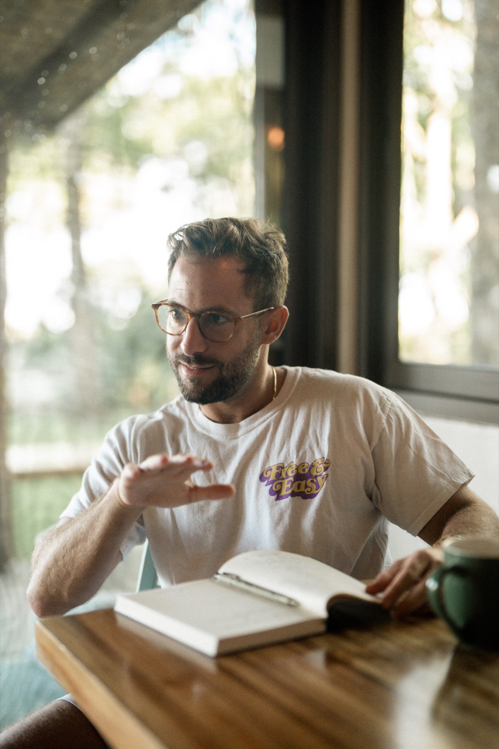 Ben Lee in conversation across a wooden table, with a notebook and a mug