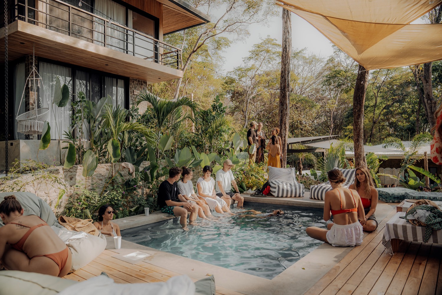 Guests lounging around a small pool under a shade sail