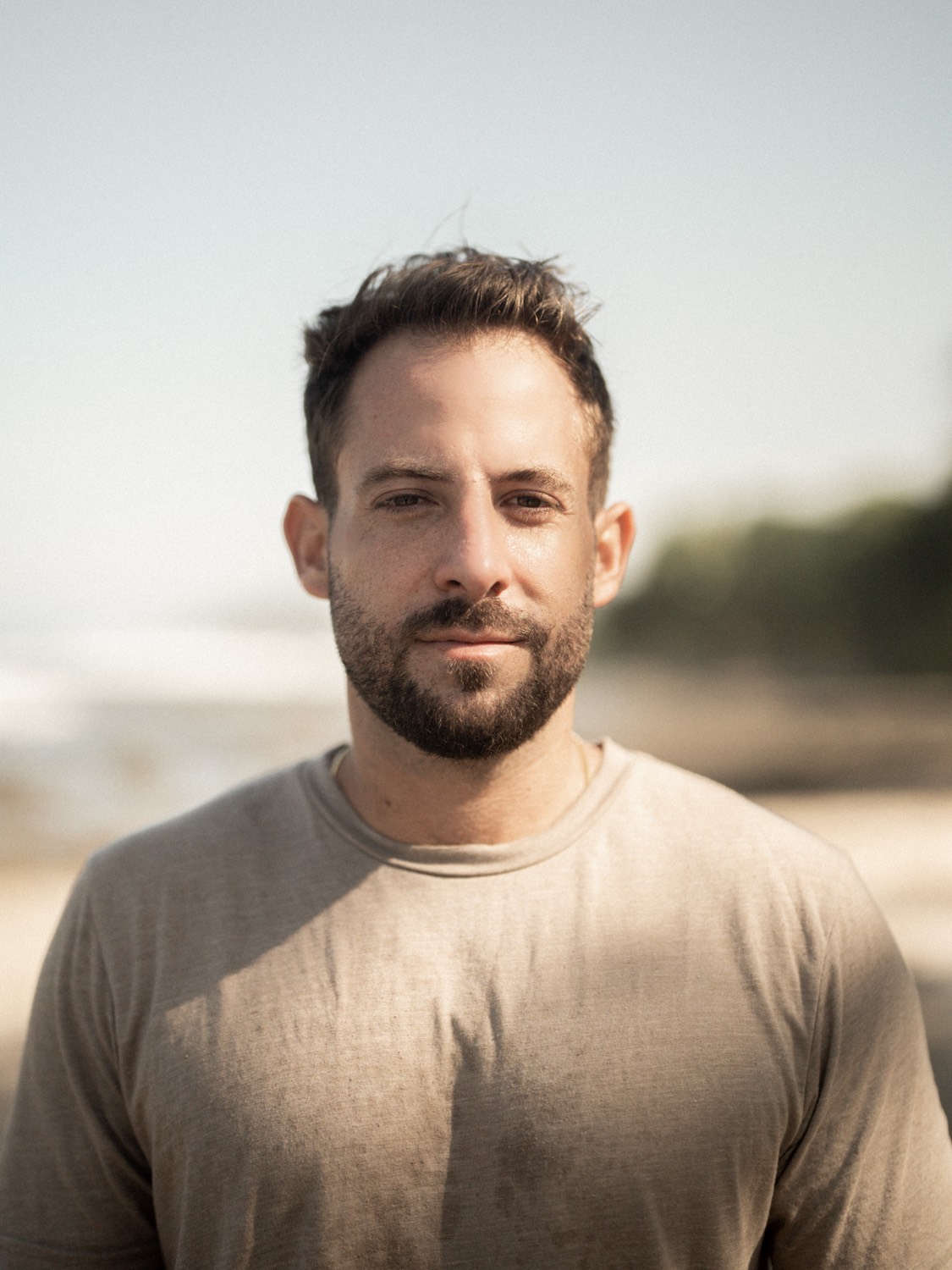 Portrait of Ben Lee smiling, outdoors in warm light